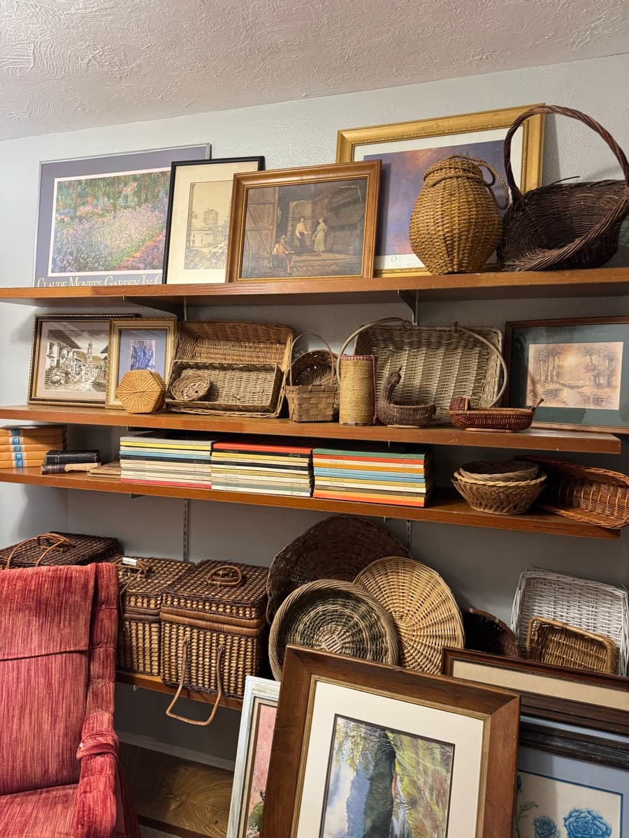 Shelves of woven baskets, framed artwork, and books inside a Salem Oregon estate sale home